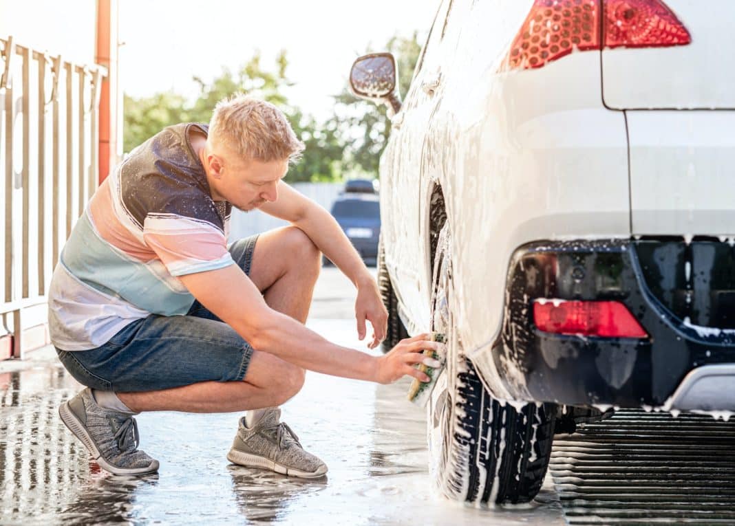 Man is washing car using sponge