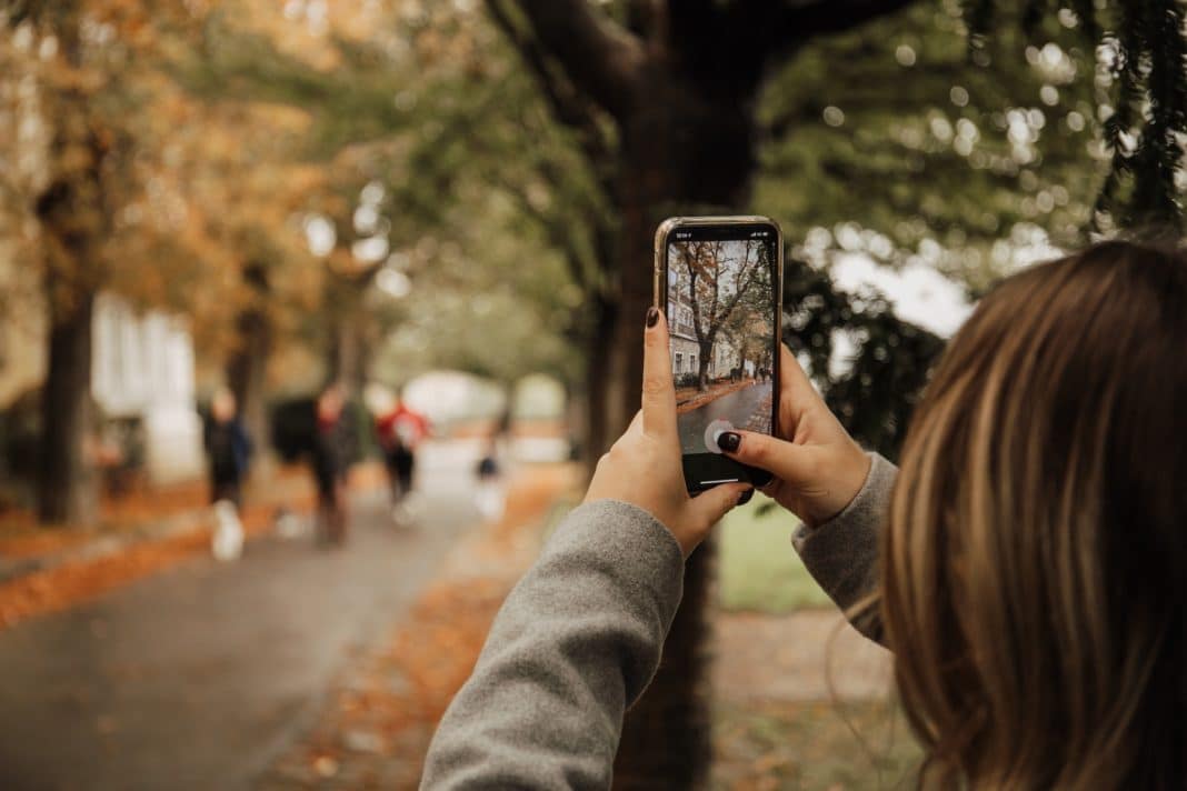 Young woman taking a picture with an iPhone