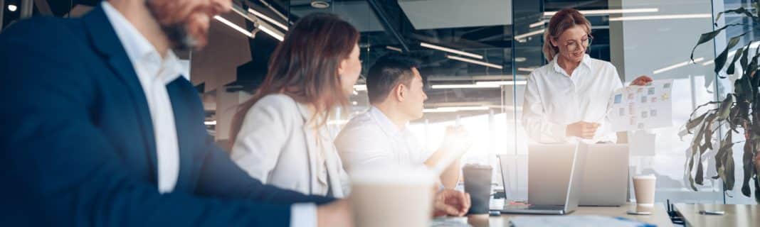 mature confident businesswoman addressing colleagues at a meeting in modern office