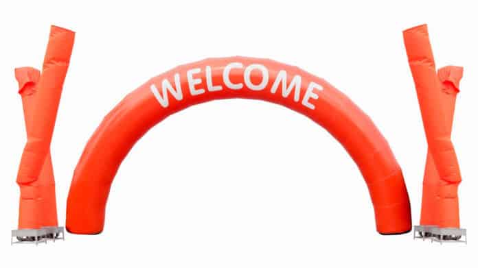 orange curve balloon with white text WELCOME and fan blowing bal