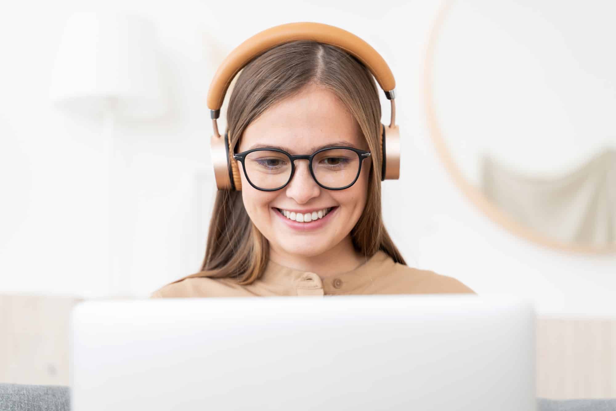 Laughing freelance girl spending time at home, working on laptop, listening to conference call
