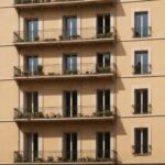 Immeuble français avec volets fermés et balcon ombragé sous une chaleur intense