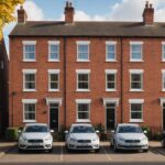 Row of British terraced homes with loft insulation rolls in a doorway and an air source heat pump outside